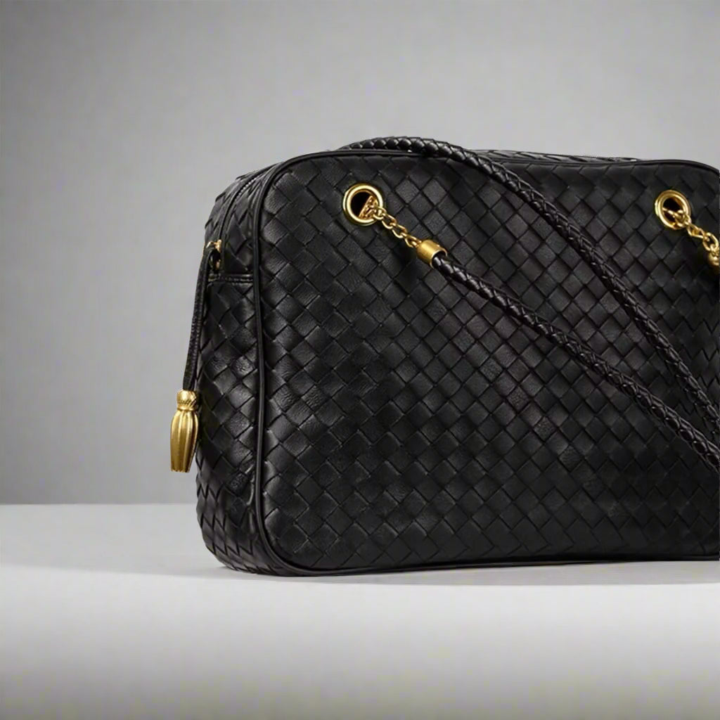 Black woven handbag with gold accents on a white surface